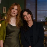 Dos mujeres aparecen juntas en una cocina cálida y acogedora, en una escena promocional inspirada en una película de fantasía y drama.