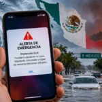 Celular mostrando una alerta de emergencia ante huracanes y fenómenos naturales en México.