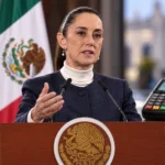 Claudia Sheinbaum al centro durante un mensaje oficial, acompañada de una terminal bancaria, un teléfono móvil y dinero mexicano como representación de los pagos digitales.